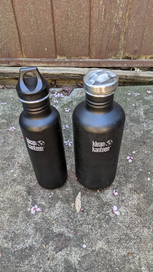 The Klean Kateen 27oz beside the bigger version of the same water bottle, with a metal lid.